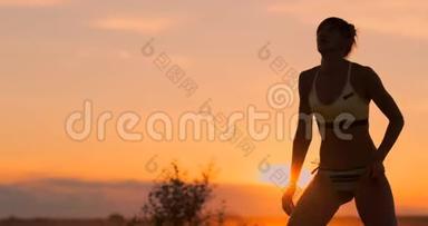 日落时分穿着比基尼的漂亮排球女孩前臂在比赛中<strong>超越</strong>队友，